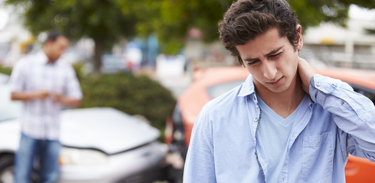 young man holding his neck in pain after whiplash due to a car accident