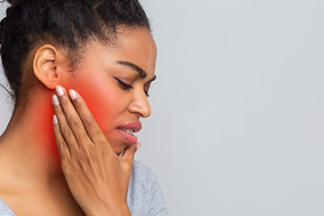 woman hold her jaw in pain due to TMJ syndrome