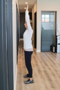 young woman in a standing position with arm stretched upward