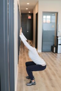 young woman in a squat position with arm stretched upward