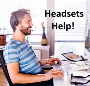 man sitting at a desk in front of a computer using a headset