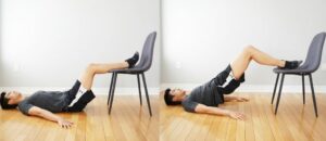 man performing a bridging exercise with feet resting on a chair