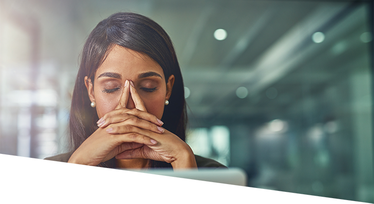 Woman sitting in front of computer stressed out with eyes closed and hands on her face