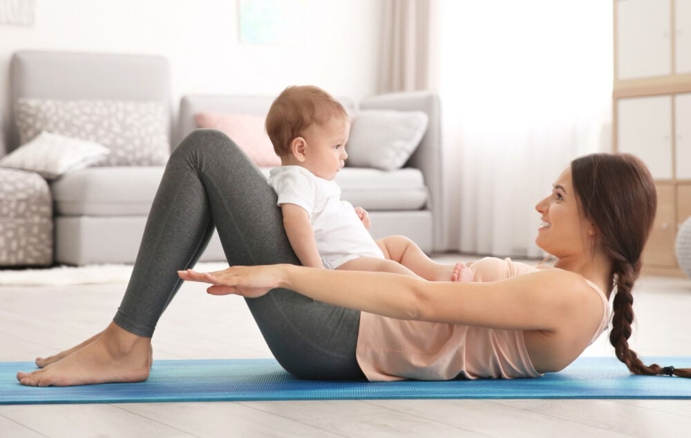 post partum woman exercising with her baby