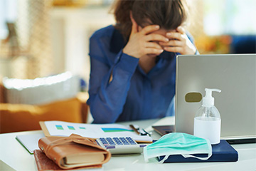 woman holding head at desk due to long covid