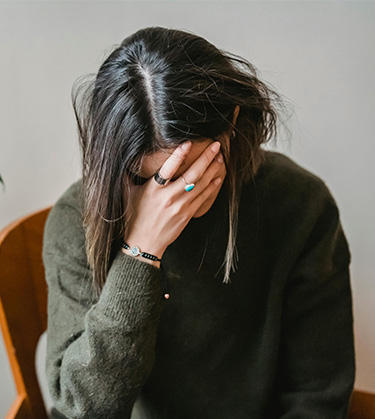 young women with her head hung low and hand on her face due to fatigue due to long covid