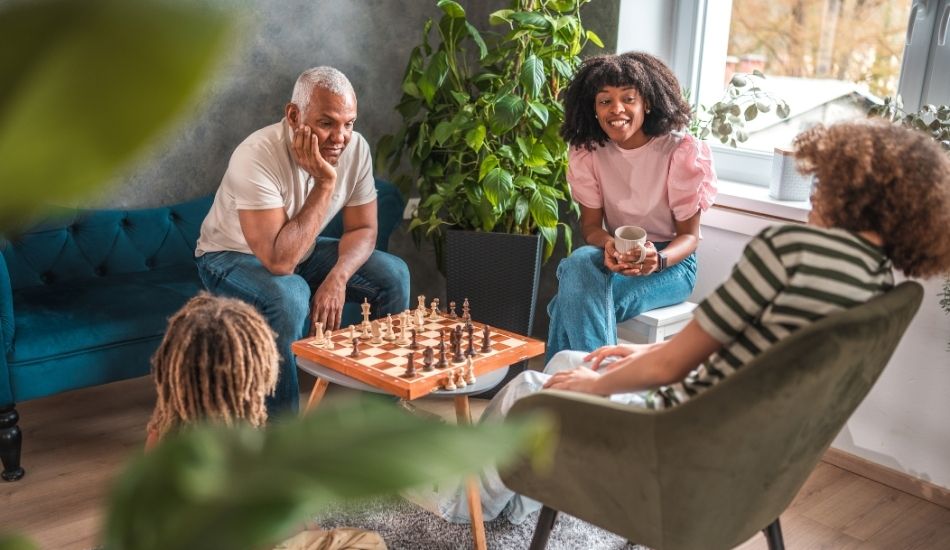 Multi generational family sit around a table with a chess board