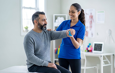 female-physiotherapist-treating-a-middle-aged-man's-shoulder-at-square-one-mississauga-physiotherapy-clinic