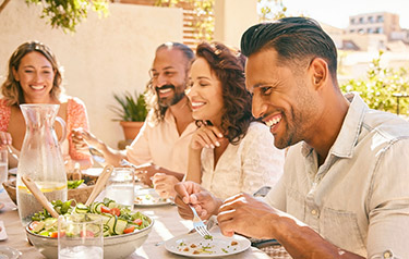 group-of-friends-smiling-and-eating-a-meal-together---hero