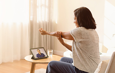 woman-stretching-her-arm-with-help-from-a-physiotherapist-virtually-for-fibromyalgia-hero