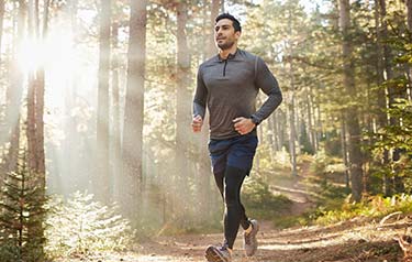Lung-Cancer-rehabilitation-A-middle-aged-man-enjoying-a-power-walk-through-a-crisp-pine-forest,-bright-sunli-570362